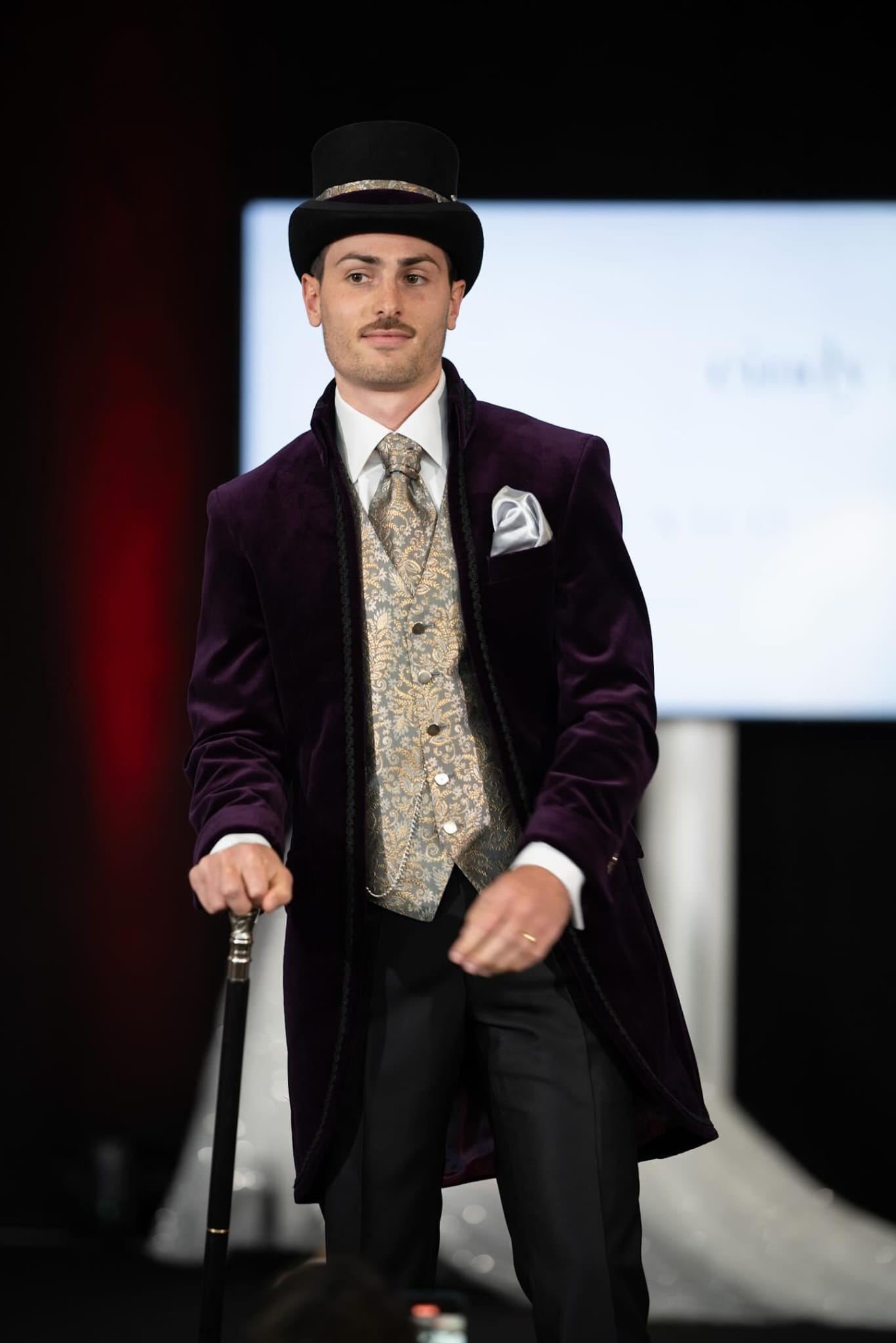 Männliches Model mit Bart, dass ein maßgeschneidertes Outfit trägt bestehend aus Zylinder, Gehrock, Weste und Plastron